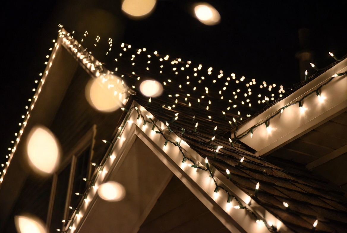 Close-up detail of neatly installed professional Christmas string lights on roofline and eaves at night